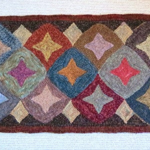 May include: Handmade rectangular rug with a repeating diamond pattern. Each diamond contains a star shape and is filled with various colors, including blue, red, yellow, and purple. The rug has a dark brown border.