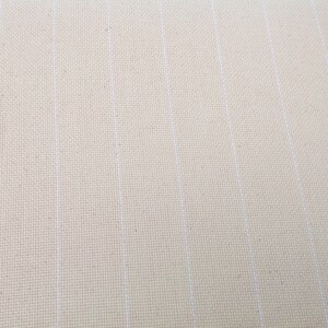 Peut inclure: Gros plan sur un tissu de point de croix cr&egrave;me avec des lignes blanches verticales. Le tissu a un aspect textur&eacute;, avec des fils tiss&eacute;s visibles. Les lignes blanches sont espac&eacute;es uniform&eacute;ment, cr&eacute;ant un motif quadrill&eacute;. Id&eacute;al pour les projets de point de croix.
