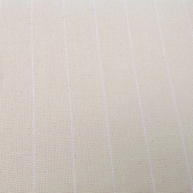 Peut inclure: Gros plan sur un tissu de point de croix cr&egrave;me avec des lignes blanches verticales. Le tissu a un aspect textur&eacute;, avec des fils tiss&eacute;s visibles. Les lignes blanches sont espac&eacute;es uniform&eacute;ment, cr&eacute;ant un motif quadrill&eacute;. Id&eacute;al pour les projets de point de croix.