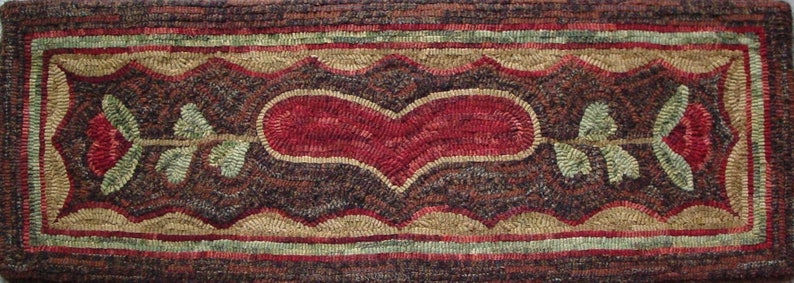 May include: A rectangular, hand-stitched rug with a central red heart design. The rug features a dark brown background with a border of red, green, and tan. Two red roses with green leaves flank the heart.