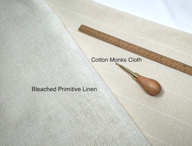 May include: An overhead shot shows two types of fabric: Bleached Primitive Linen and Cotton Monks Cloth. A wooden ruler with inch markings and a wooden-handled needle tool are also present. The fabrics are off-white and beige.