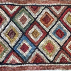 May include: Close-up of a hand-hooked rug with a repeating diamond pattern. The diamonds are filled with various colors, including red, blue, green, and yellow, and are outlined in black. The rug has a textured appearance.