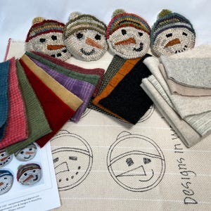 May include: A collection of handmade snowman-themed crafts and materials. Includes several small, round, stitched snowman faces with colorful hats, fabric swatches in various colors, and a patterned fabric with snowman outlines.