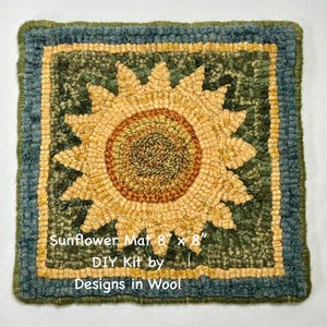 May include: Handmade sunflower rug, 8 x 8 inches, with a yellow and brown sunflower design on a green background. The rug has a blue border and the text "Sunflower Mat 8" x 8" DIY Kit by Designs in Wool".