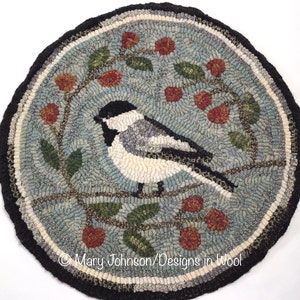May include: Round, hand-hooked rug featuring a bird perched on a branch with berries. The rug has a light blue background with a black border. The bird is black, white, and gray. The rug measures approximately 24 inches in diameter.