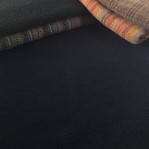 Peut inclure: Gros plan sur des textiles pli&eacute;s dans des tons de marron, orange et bleu. Les tissus pr&eacute;sentent divers motifs, notamment des rayures et des carreaux. L'image met en &eacute;vidence les textures et les couleurs des mat&eacute;riaux. Les textiles semblent doux.