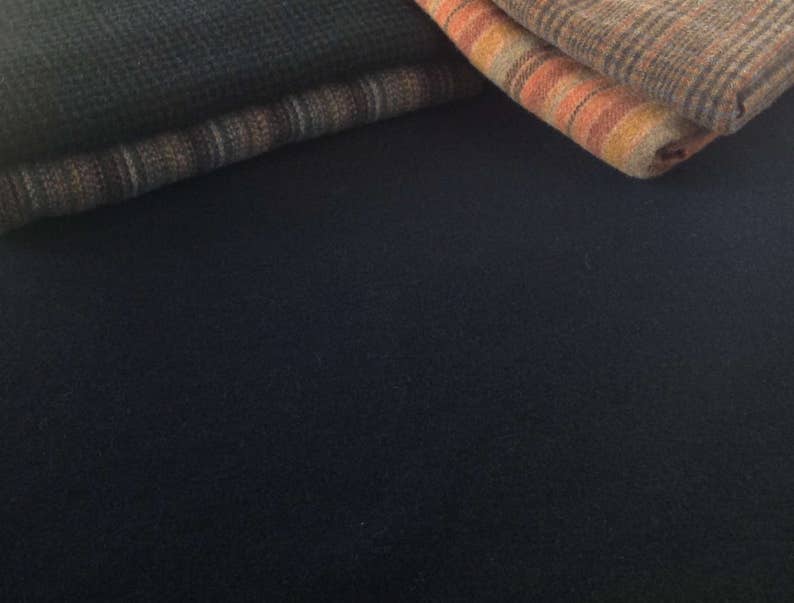 Peut inclure: Gros plan sur des textiles pli&eacute;s dans des tons de marron, orange et bleu. Les tissus pr&eacute;sentent divers motifs, notamment des rayures et des carreaux. L'image met en &eacute;vidence les textures et les couleurs des mat&eacute;riaux. Les textiles semblent doux.