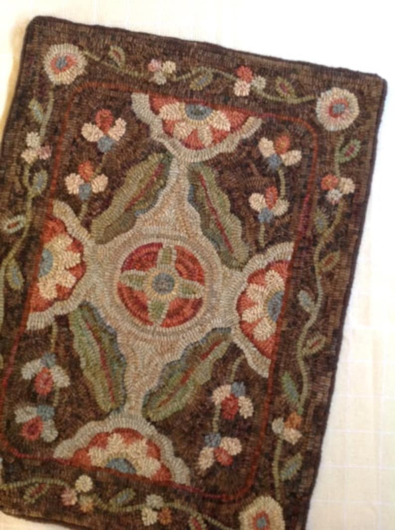 Puede incluir: Una alfombra rectangular hecha a mano con un dise&ntilde;o floral. La alfombra presenta un fondo marr&oacute;n oscuro con un medall&oacute;n central y motivos florales en las esquinas en tonos de rojo, verde, azul y crema. El borde de la alfombra tambi&eacute;n es marr&oacute;n oscuro.