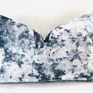 May include: A decorative throw pillow with a white and gray abstract pattern on a dark blue background.