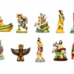 May include: A collection of ten hand-painted ceramic figurines depicting various figures and symbols, including individuals in canoes, on horseback, standing in traditional attire, a winged totem-style bird, and a colorful cylindrical character.