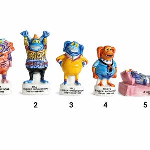 Può includere: Una collezione di cinque figurine in ceramica colorate. Ogni figurina raffigura un personaggio dei cartoni animati unico con caratteristiche e pose distinte. Le figurine sono numerate e hanno testo sulla base, incluso il nome e la società di produzione.