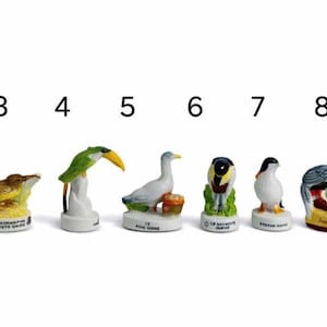 May include: A collection of ten small, ceramic bird figurines. Each bird is uniquely colored and perched on a white base with a nameplate. The birds include a penguin, hawk, and toucan, among others. The figurines are numbered 1 through 10.
