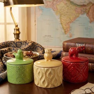 May include: A set of three ceramic mugs with a speckled, matte finish. The mugs are in shades of cream, light gray, and dark gray. Each mug has a simple, minimalist design, perfect for coffee or tea.