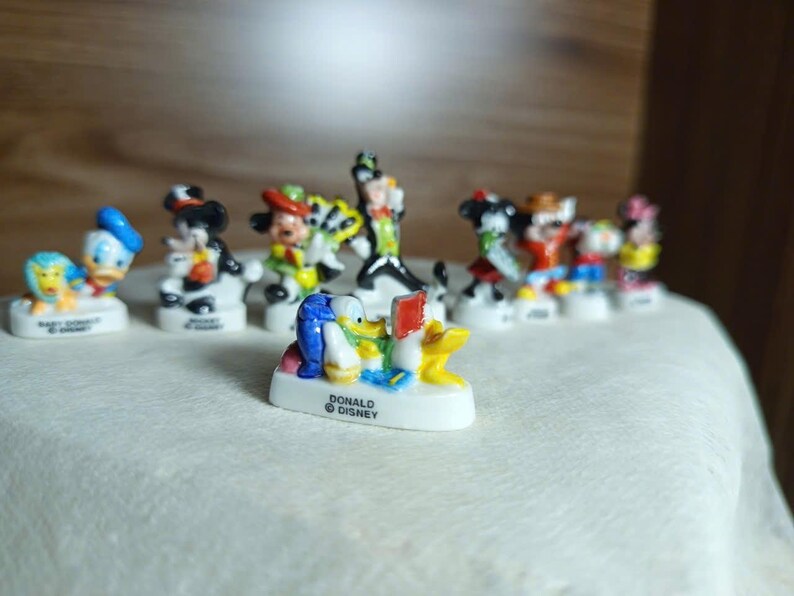 以下が含まれることがあります： ミッキーマウス、ドナルドダックなど、ディズニーのキャラクターの小さなカラフルなフィギュアのコレクション。各フィギュアは、キャラクターの名前が書かれた小さな白いベースに取り付けられています。フィギュアは明るい色で、細部までこだわっています。