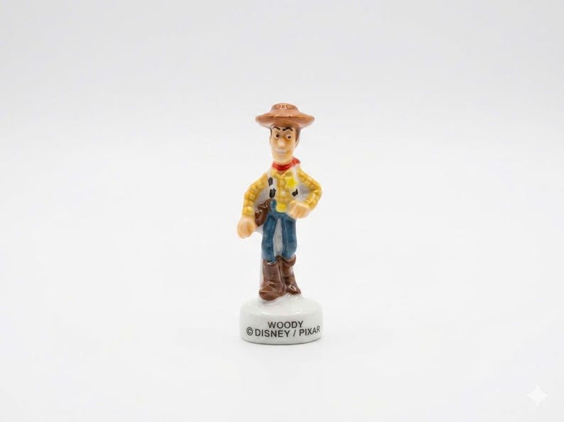 Pu&ograve; includere: Una piccola statuina di Woody di Toy Story della Disney/Pixar. La figura indossa un cappello da cowboy marrone, una camicia a quadri gialla, jeans blu e stivali marroni. La base &egrave; bianca con il nome "WOODY" e il logo Disney/Pixar.