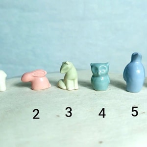 May include: A collection of six small animal figurines in various colors. Includes a white bear, pink rabbit, light green horse, teal owl, blue penguin, and a light green deer. Each figurine is numbered from 1 to 6.