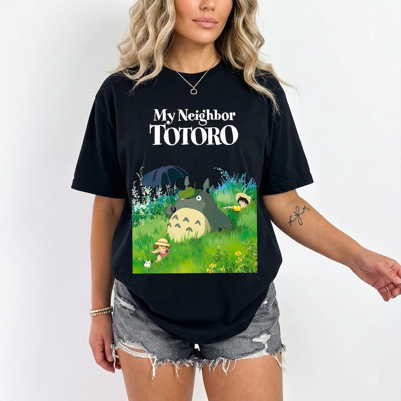 May include: Black t-shirt featuring the text "My Neighbor TOTORO" in white. The graphic depicts Totoro and other characters in a grassy field. The shirt is a short-sleeved, crew neck style.
