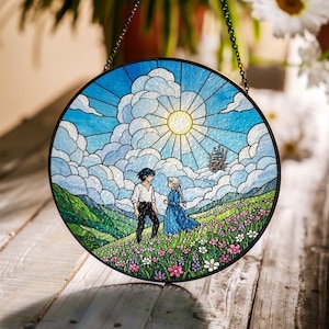 May include: Round stained glass window art featuring a sunny sky with fluffy clouds, a castle, and two figures in a field of flowers. The artwork is framed in black and hangs from a chain.