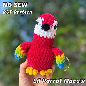 May include: A handmade crochet parrot in vibrant red, white, black, yellow, blue, and green. The text "NO SEW PDF Pattern" and "Lil Parrot Macaw" are displayed. The parrot has a textured, plush appearance.