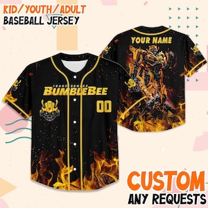 Può includere: Maglia da baseball nera con dettagli gialli e un design Bumblebee Transformers. La maglia presenta il testo "BUMBLEBEE" e il numero "00". Il retro ha una sezione "YOUR NAME" e una grafica di Bumblebee.