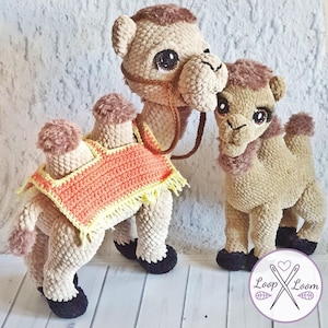 May include: Two crochet camels in beige with brown accents. One larger camel has a saddle and bridle, and a smaller camel stands beside it. The camels have black hooves and large, expressive eyes. The logo "Loop Loom" is in the bottom right corner.
