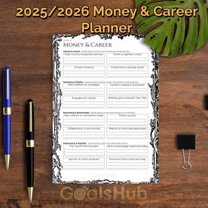 Könnte beinhalten: Ein Finanz- und Karriereplaner für 2025/2026 mit detailliertem Layout. Das Bild zeigt einen blauen Stift, einen schwarzen Stift und zwei schwarze Büroklammern auf einer Holzoberfläche. Ein grünes Blatt ist im Hintergrund.