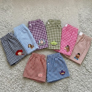 Può includere: Una collezione di pantaloncini a quadri colorati con toppe di personaggi di Toy Story. I pantaloncini sono disponibili in una varietà di colori, tra cui nero, blu, viola, verde, rosa e marrone. Ogni paio ha una toppa diversa.