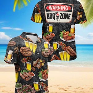 Puede incluir: Camisa negra con botones con temática de barbacoa. La camisa presenta imágenes de carnes a la parrilla, jarras de cerveza y el texto "WARNING BBQ ZONE". El fondo es una escena de playa con palmeras y arena.