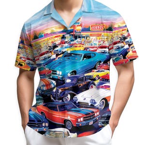 May include: A short-sleeved button-down shirt featuring a vibrant print of classic cars parked in front of an arcade. The design includes a variety of colorful vintage vehicles and a sunset sky. The shirt has a light blue collar and a relaxed fit.