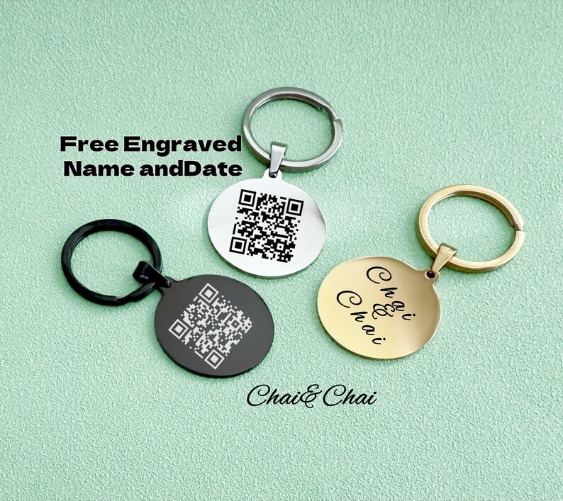 May include: Three round keyrings with different coloured metal rings. One is silver, one is black, and one is gold. The silver and black keyrings have a QR code engraved on them. The gold keyring has the words "Chai & Chai" engraved on it.