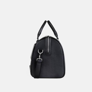 Pu&ograve; includere: Borsa da viaggio nera con cerniera argentata e tracolla staccabile. La borsa ha due manici superiori e una forma rettangolare. Realizzata in materiale liscio, ideale per viaggi o palestra.