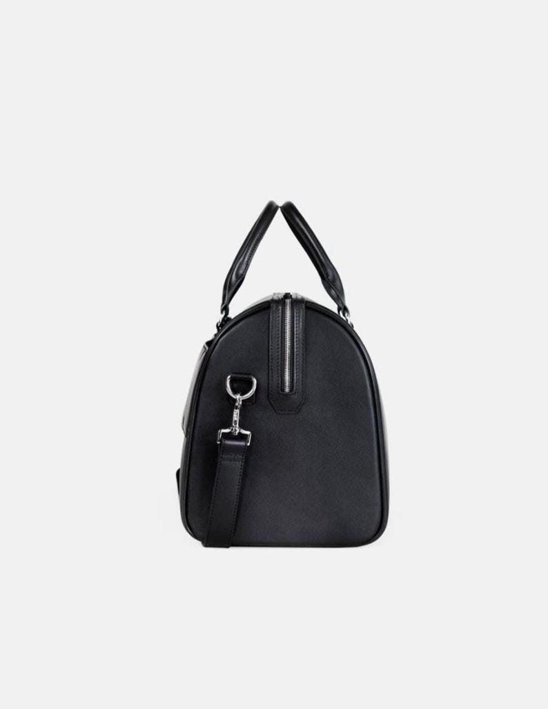 Pu&ograve; includere: Borsa da viaggio nera con cerniera argentata e tracolla staccabile. La borsa ha due manici superiori e una forma rettangolare. Realizzata in materiale liscio, ideale per viaggi o palestra.