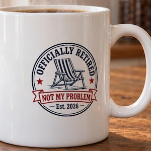May include: A white ceramic mug featuring a circular graphic with a blue striped beach chair in the centre. The text reads "OFFICIALLY RETIRED" in blue, "NOT MY PROBLEM" in red on a banner, and "Est. 2026" at the bottom with two red stars.