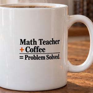 May include: A white ceramic mug featuring black text that reads Math Teacher + Coffee = Problem Solved. The plus sign is printed in orange. The mug has a standard cylindrical shape with a curved handle on the right side and is filled with dark coffee.