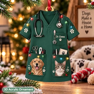 May include: A dark green V-neck scrub top ornament featuring a stethoscope, a pocket with the text Dr. Emma, and illustrations of a golden retriever and a tabby cat. The garment is decorated with colorful Christmas lights and paw print motifs.