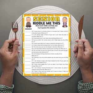 May include: A senior riddle game sheet with the text "SENIOR RIDDLE ME THIS" and illustrations of elderly people. The sheet is on a plate with a fork and knife on either side.