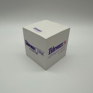 May include: A white cube-shaped notepad featuring the Zithromax logo in purple text. The front side displays Zithromax IV azithromycin for injection, while the side panel reads Zithromax available as Z-PAK azithromycin 250 mg tablets.