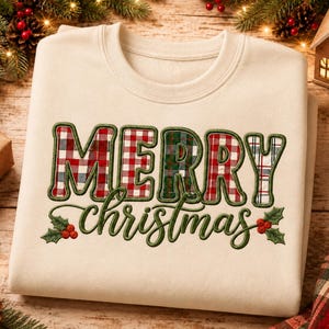 May include: A cream-colored crewneck sweatshirt featuring the text MERRY CHRISTMAS in a bold, embroidered style. The letters are filled with various red, green, and white plaid patterns, and the word christmas is accented with holly leaves and berries.