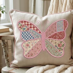 May include: A square beige throw pillow featuring a large, central butterfly appliqué. The butterfly wings are composed of various patchwork fabric segments in shades of pink, blue, and red, featuring floral, gingham, and plaid patterns with pink piping.