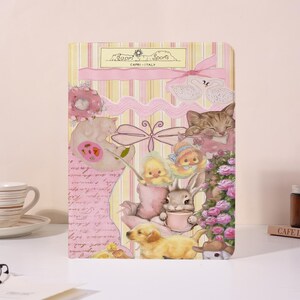 May include: A decorative notebook with a collage of cute animal illustrations, including a kitten, bunny, and puppy. The notebook has a pink and yellow striped background with the text "Capri Sports - Capri - Italy".