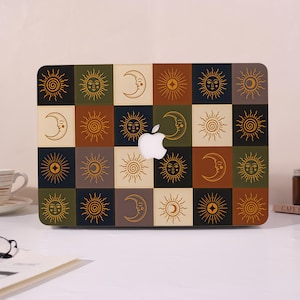 May include: A rectangular laptop hard shell case featuring a grid pattern of alternating squares in shades of olive green, cream, dark brown, and black. Each square contains a gold-toned line art illustration of a sun or a crescent moon face.
