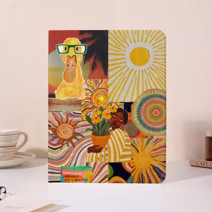 May include: A colorful tablet case featuring a collage of illustrations. The design includes a yellow duck wearing glasses, suns, and a person holding a flower pot. The text "ACTUALLY LIFE IS BEAUTIFUL" is visible.