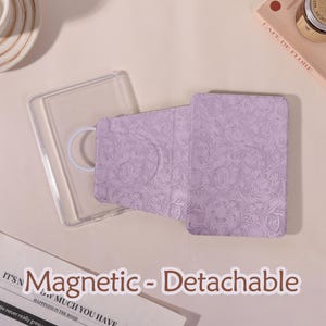 May include: A lavender magnetic and detachable case for an electronic device. The case has a floral pattern and a clear plastic frame. The text "Magnetic - Detachable" is visible in the image.