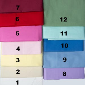 May include: A collection of folded fabric swatches in various colors, including white, cream, yellow, pink, red, blue, and green. Each swatch is labeled with a number from 1 to 12, providing a visual guide to the color options.