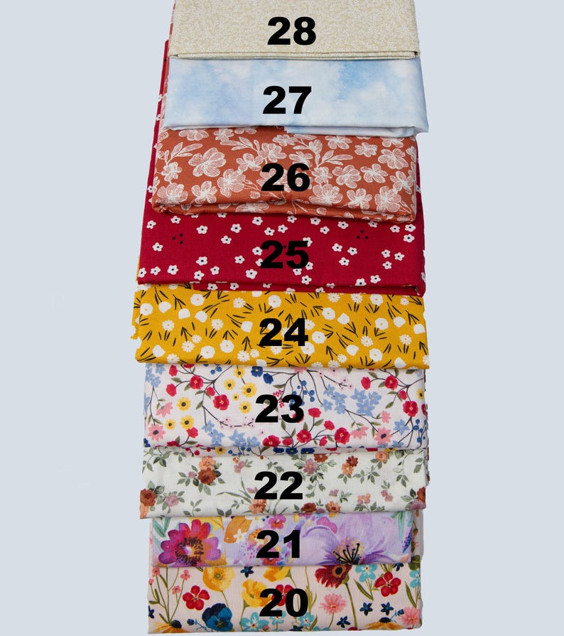 May include: A stack of fabric swatches in various floral and patterned designs. The colors include red, yellow, blue, and cream. Each swatch is labeled with a number from 20 to 28.