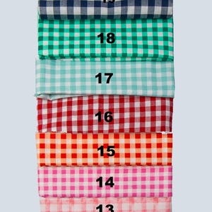 May include: A stack of fabric samples in various colors, each with a gingham pattern. Colors include navy blue, green, light blue, red, orange, pink, and light pink. Numbers 13 through 19 are printed on the fabric.