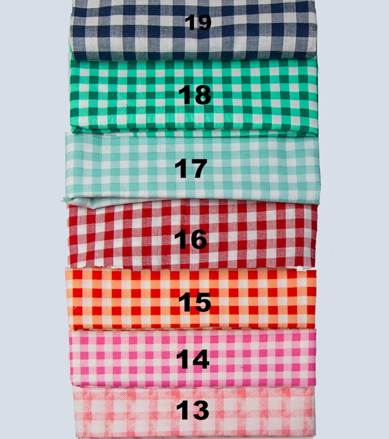 May include: A stack of fabric samples in various colors, each with a gingham pattern. Colors include navy blue, green, light blue, red, orange, pink, and light pink. Numbers 13 through 19 are printed on the fabric.