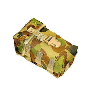 Könnte beinhalten: Eine rechteckige Tasche mit Tarnmuster und einem beigefarbenen Schnallenverschluss und Riemen. Die Tasche hat ein Muster aus Grün-, Braun- und Beigetönen. Die Riemen und die Schnalle sind hellbeige. Zum Tragen von Gegenständen.