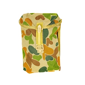 May include: A camouflage pouch in tan, brown, green, and orange. It features a flap closure with a yellow strap and buckle. The pattern is similar to military camouflage, suggesting a utility design.
