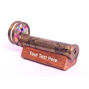 Close-up of gemstone lens on handcrafted brass kaleidoscope

Engraved wooden stand holding luxury brass kaleidoscope collectible

Handmade brass kaleidoscope gift for art lovers and collectors

Artisan brass kaleidoscope with gemstone lens and classic wooden stand

Collectible brass kaleidoscope optical instrument with engraved wood base